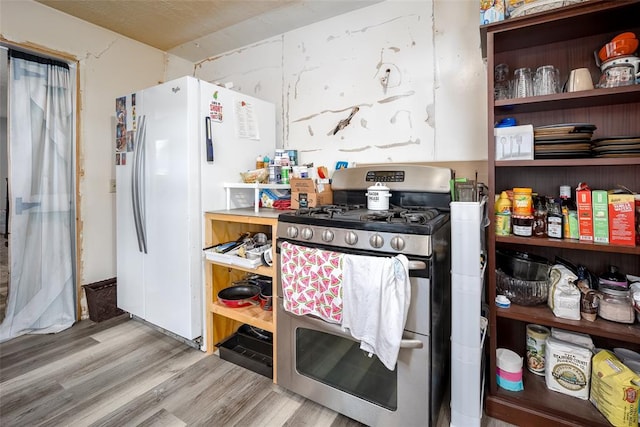 kitchen with white fridge, stainless steel range with gas cooktop, and light hardwood / wood-style flooring