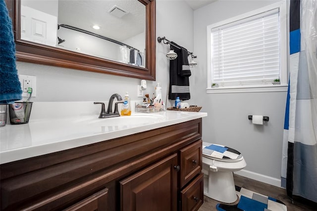 bathroom with toilet, vanity, and hardwood / wood-style flooring