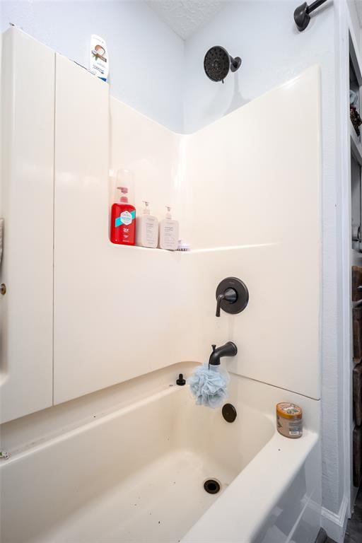 bathroom with a textured ceiling and  shower combination