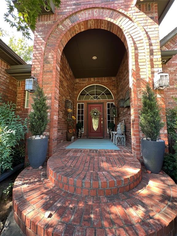 entrance to property featuring a porch and brick siding