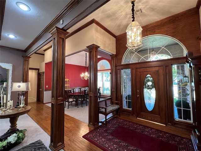 entryway with decorative columns, a chandelier, and wood finished floors