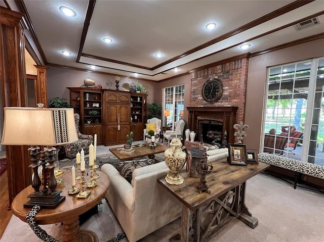 carpeted living area featuring a tray ceiling, a brick fireplace, visible vents, and recessed lighting