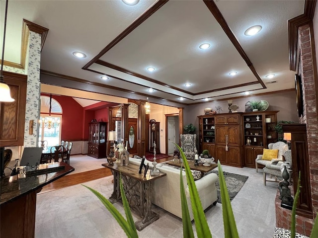 living room with a brick fireplace, a raised ceiling, crown molding, and decorative columns