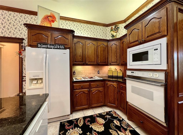 kitchen featuring crown molding, light tile patterned floors, dark stone countertops, white appliances, and wallpapered walls