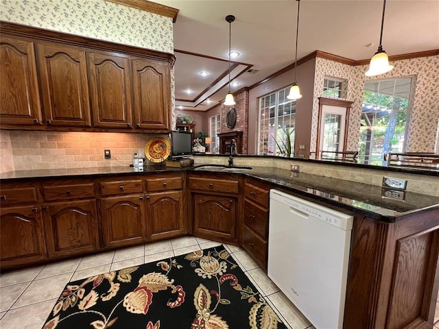 kitchen featuring crown molding, white dishwasher, dark stone counters, and a sink