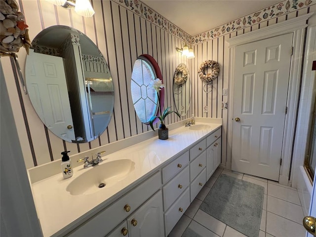 full bathroom with double vanity, wallpapered walls, tile patterned flooring, and a sink