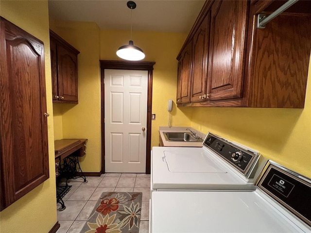 clothes washing area with cabinet space, light tile patterned floors, baseboards, independent washer and dryer, and a sink