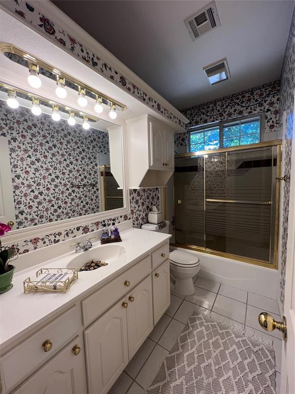 full bathroom featuring enclosed tub / shower combo, tile patterned flooring, toilet, vanity, and visible vents