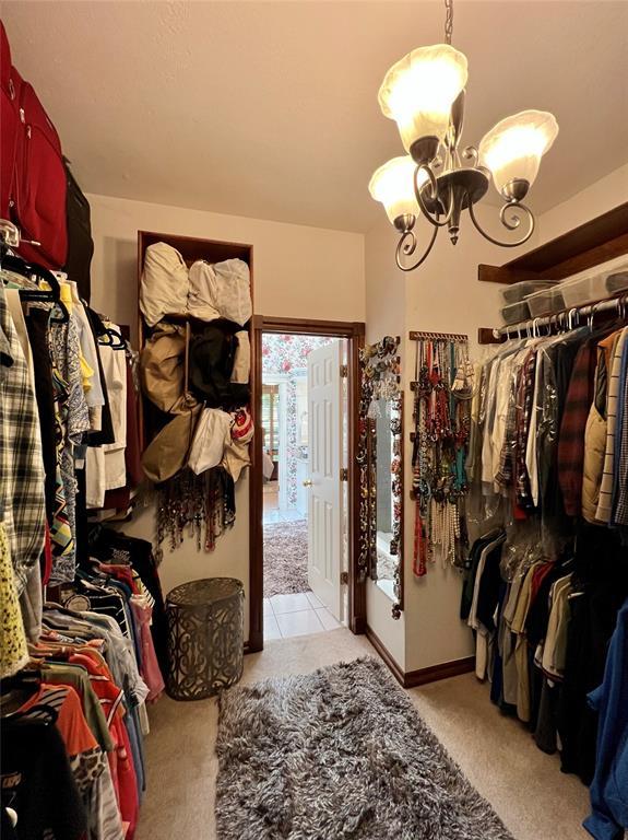 walk in closet featuring a chandelier and carpet floors