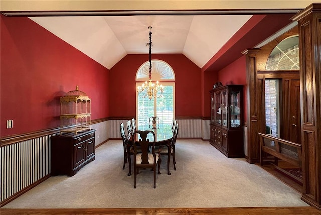 dining area featuring a wainscoted wall, vaulted ceiling, an inviting chandelier, and light colored carpet