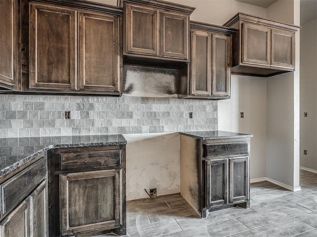 kitchen featuring dark brown cabinets, backsplash, and dark stone counters