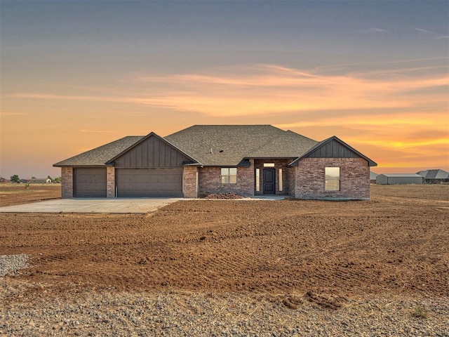 view of front of house with an attached garage, brick siding, concrete driveway, board and batten siding, and a shingled roof