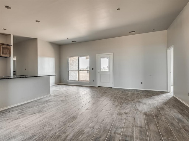 unfurnished living room featuring baseboards and wood finished floors