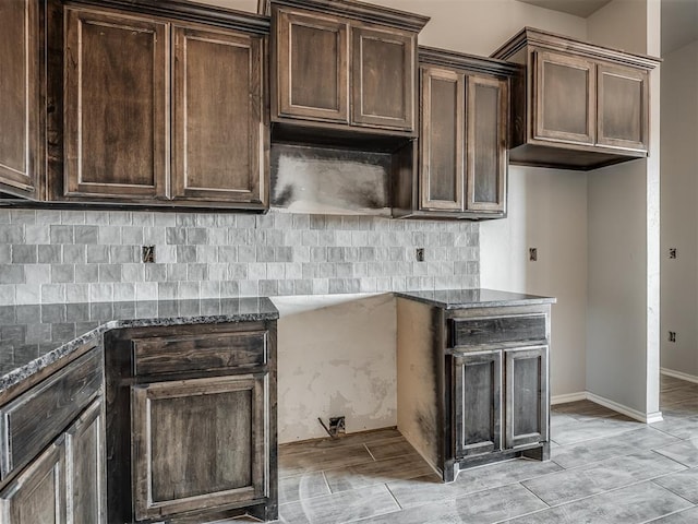 kitchen with dark brown cabinets, tasteful backsplash, and dark stone countertops