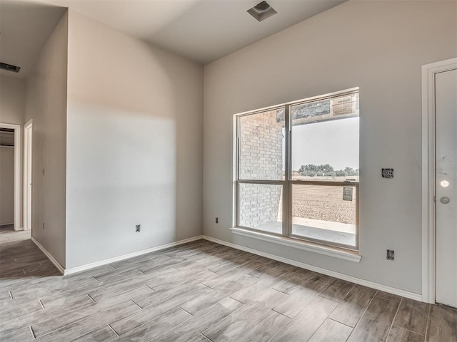 empty room with baseboards, a healthy amount of sunlight, and wood finished floors