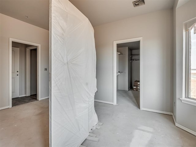 corridor featuring baseboards, visible vents, and concrete flooring