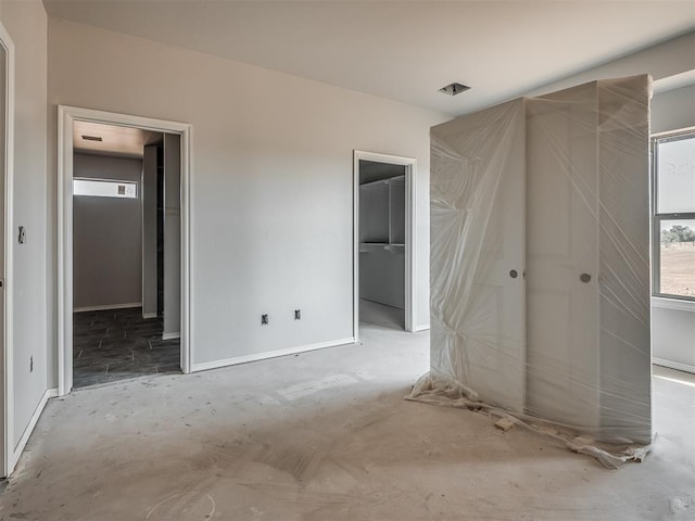 unfurnished bedroom featuring a walk in closet, baseboards, and a closet
