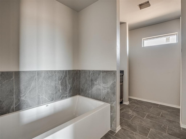 full bath featuring marble finish floor and a bath