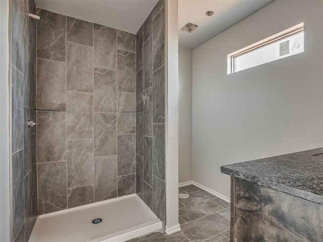 full bath with marble finish floor, baseboards, and tiled shower