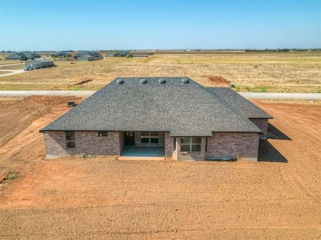 back of house featuring a patio area, brick siding, and roof with shingles