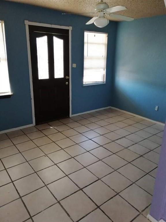 tiled entrance foyer featuring a textured ceiling and ceiling fan