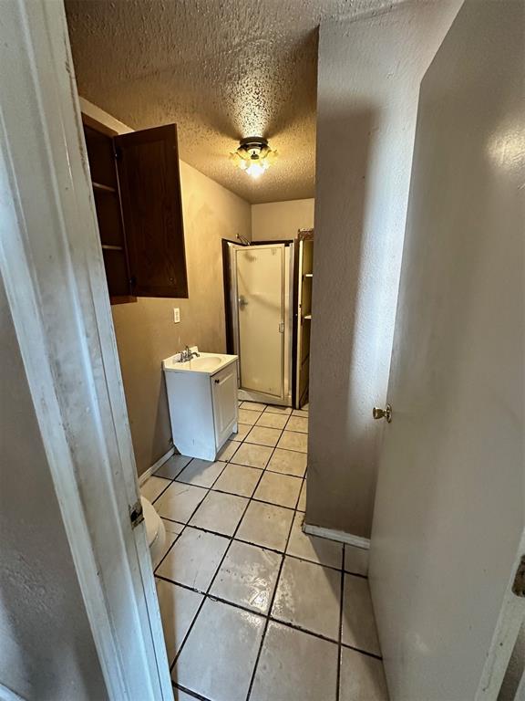 laundry area featuring sink, light tile patterned floors, and a textured ceiling