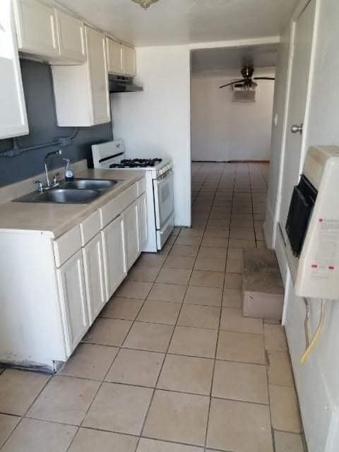 kitchen featuring gas range gas stove, ceiling fan, sink, light tile patterned floors, and white cabinets