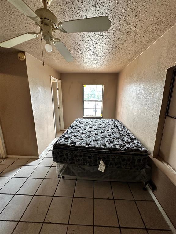 unfurnished bedroom featuring a textured ceiling, tile patterned floors, and ceiling fan