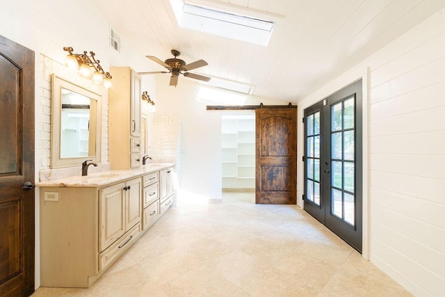 bathroom with ceiling fan, french doors, lofted ceiling with skylight, vanity, and wood ceiling