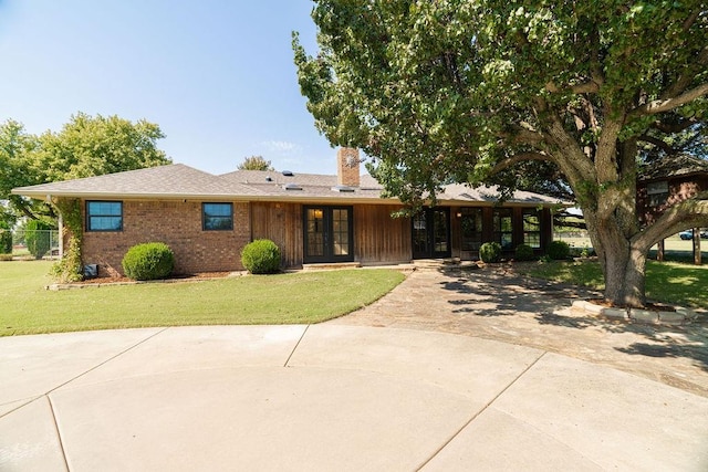 ranch-style house with a front yard and french doors