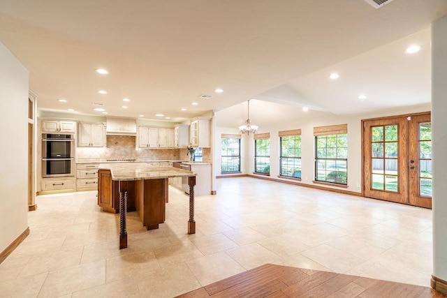 kitchen with pendant lighting, light stone counters, tasteful backsplash, a large island, and a kitchen bar