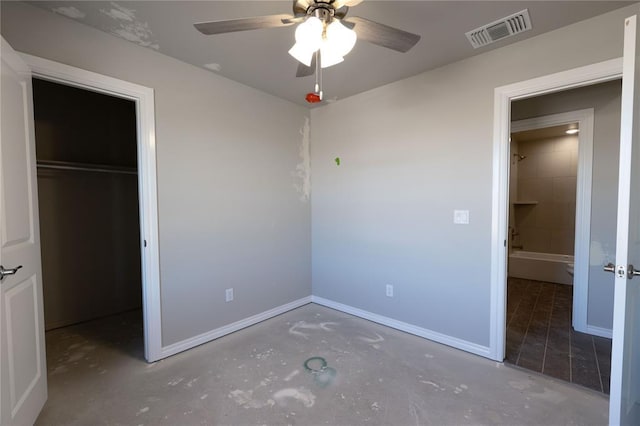 unfurnished bedroom featuring ceiling fan, a walk in closet, concrete flooring, and a closet