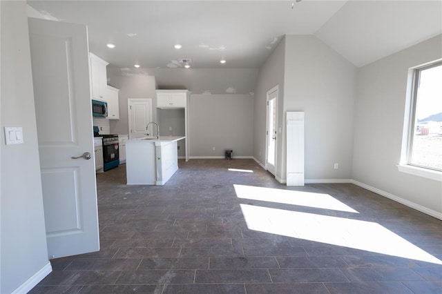 kitchen with lofted ceiling, stainless steel electric range, a wealth of natural light, and an island with sink