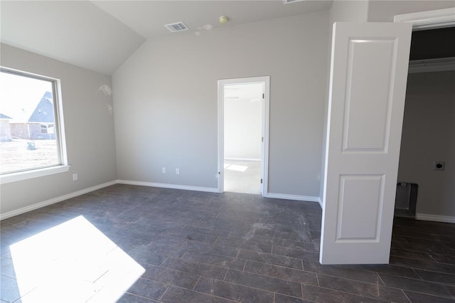 unfurnished bedroom featuring ensuite bathroom and lofted ceiling