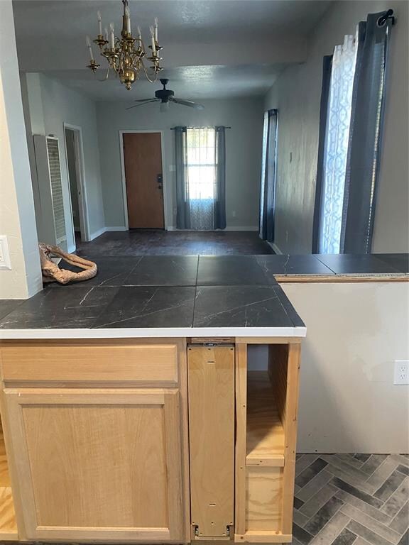 kitchen featuring light brown cabinetry and ceiling fan with notable chandelier