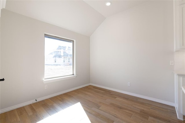 spare room featuring hardwood / wood-style flooring and vaulted ceiling