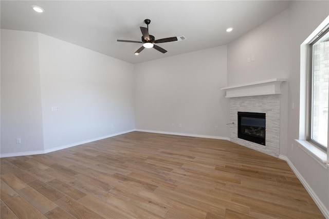 unfurnished living room featuring a fireplace, light hardwood / wood-style floors, and ceiling fan