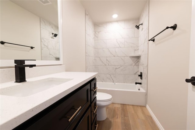 full bathroom with tiled shower / bath combo, vanity, hardwood / wood-style floors, and toilet