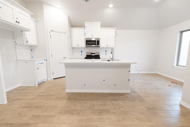 kitchen with stainless steel appliances, light countertops, white cabinetry, and a sink