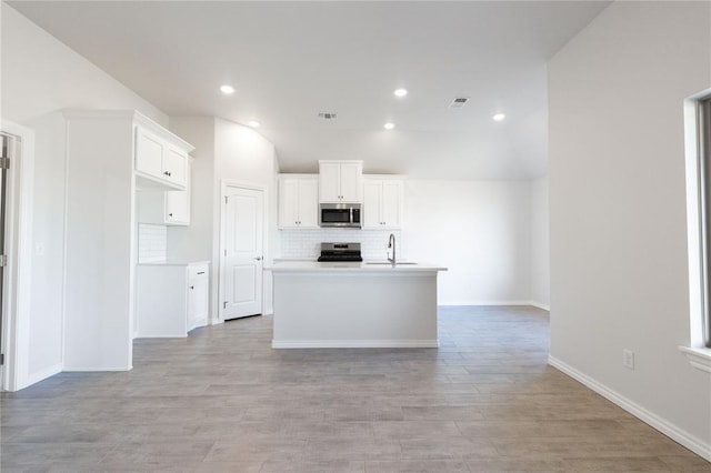kitchen featuring white cabinetry, tasteful backsplash, light wood finished floors, visible vents, and appliances with stainless steel finishes