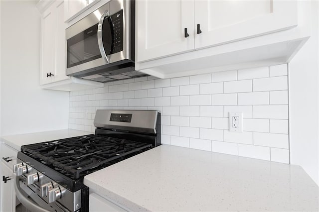 kitchen featuring white cabinets, light stone counters, backsplash, and stainless steel appliances