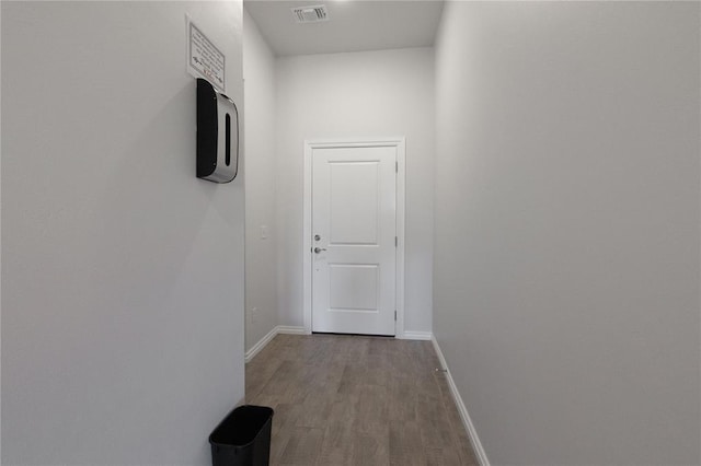 corridor with baseboards, visible vents, and wood finished floors
