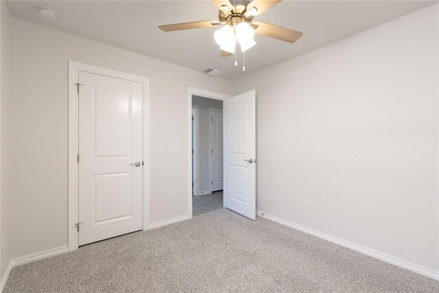 unfurnished bedroom with baseboards, visible vents, carpet floors, and a ceiling fan