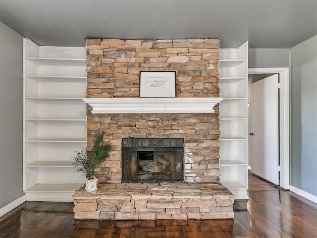 room details featuring a stone fireplace, built in features, and wood-type flooring