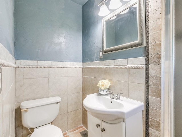 bathroom featuring vanity, toilet, and tile walls