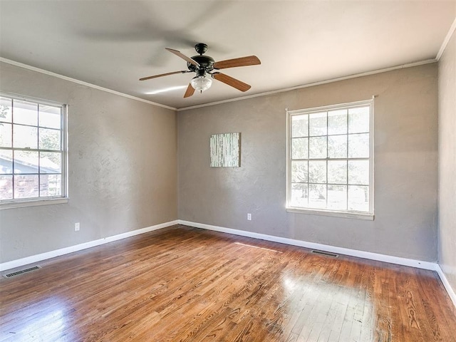 unfurnished room featuring ceiling fan, hardwood / wood-style floors, a healthy amount of sunlight, and ornamental molding