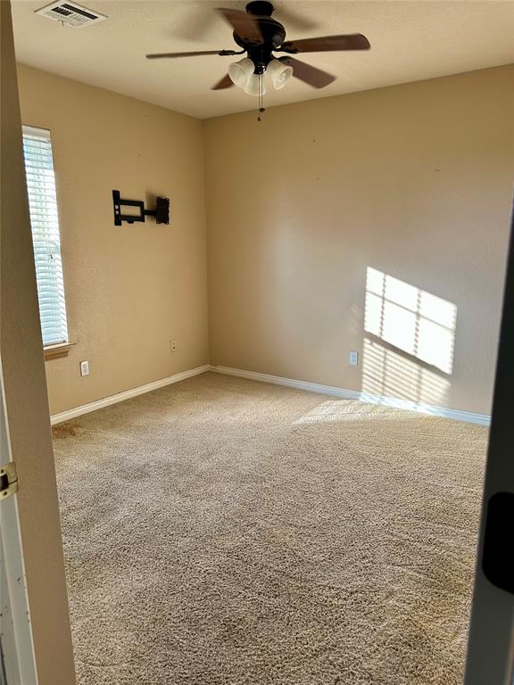 carpeted spare room with ceiling fan