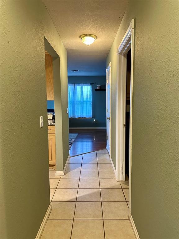 hallway featuring light tile patterned floors and a textured ceiling