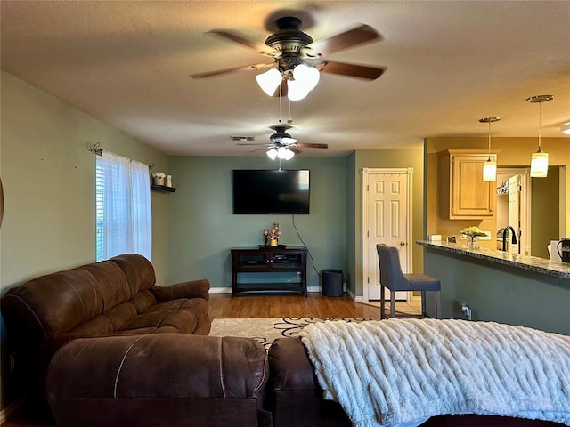 living room with a textured ceiling, light wood-type flooring, and ceiling fan