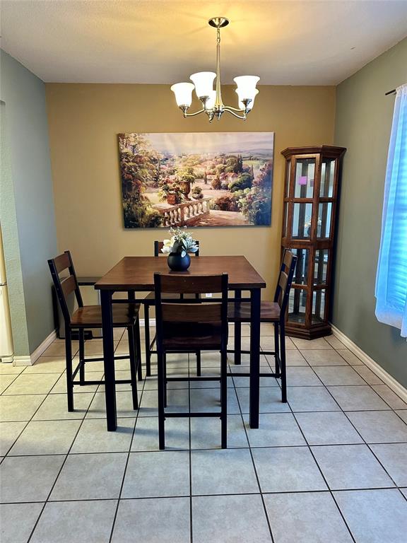 tiled dining space featuring an inviting chandelier